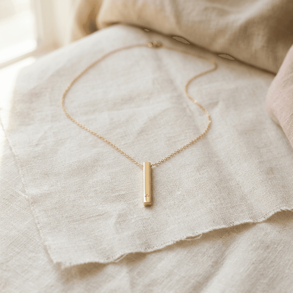 a delicate gold pendant necklace arranged on ivory linen